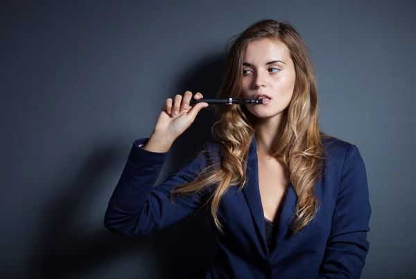 Elegante mujer fumando e-cigarrillo usando traje — Foto de Stock