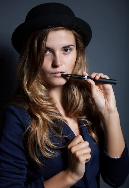 Elegante mujer fumando cigarrillo electrónico con traje y sombrero —  Fotos de Stock