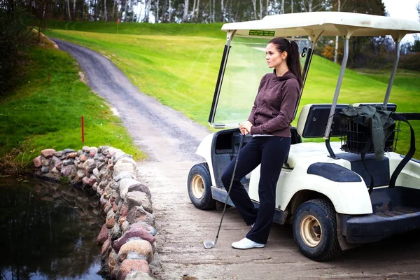 Kobieta stojąc w pobliżu golf koszyka samochodu i patrząc na widok — Zdjęcie stockowe