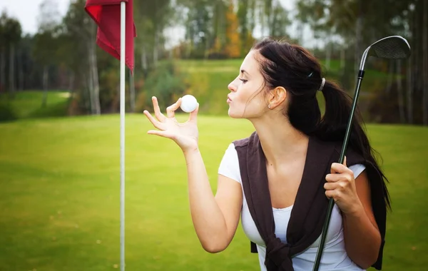 Jonge vrouw golfspeler op groen, kussen bal — Stockfoto