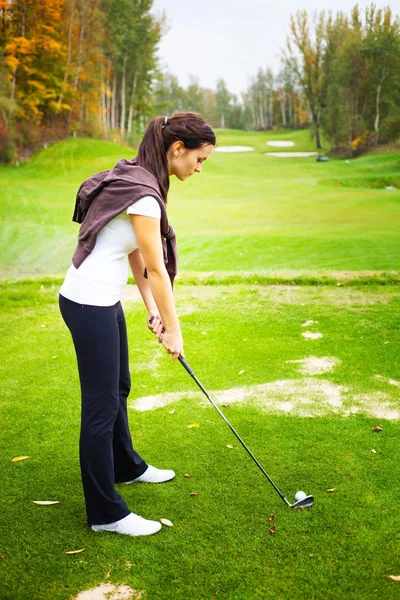 Mladá žena přehrávač na golfové hřiště, na které se chystá golf swing — Stock fotografie