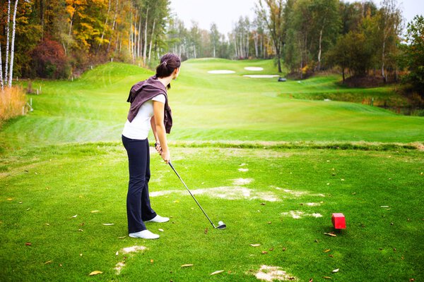 Молодая женщина игрок в гольф на поле готовится к гольф качели
