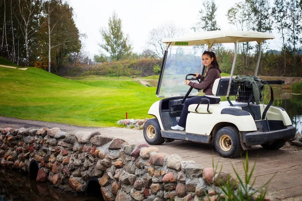 Mladá žena hnací golfový vozík — Stock fotografie