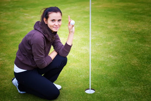 Jeune femme joueuse de golf tenant la balle donnant pouce signe — Photo