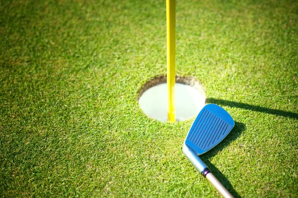 Copo de golfe com clube no fundo verde — Fotografia de Stock