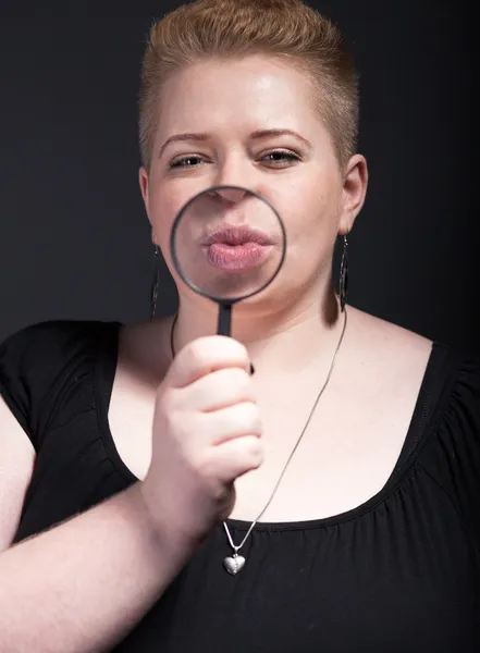 Chubby woman with magnifying glass blowing a kiss — Stock Photo, Image