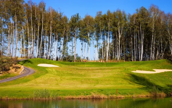 Поле для гольфа осенью, луг и озеро — стоковое фото