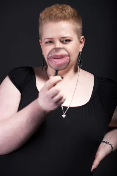 Chubby woman with magnifying glass blowing a kiss — Stock Photo, Image