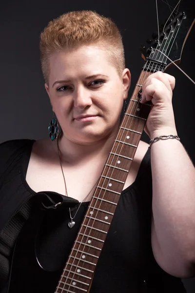 Chubby woman with short hair holding guitar