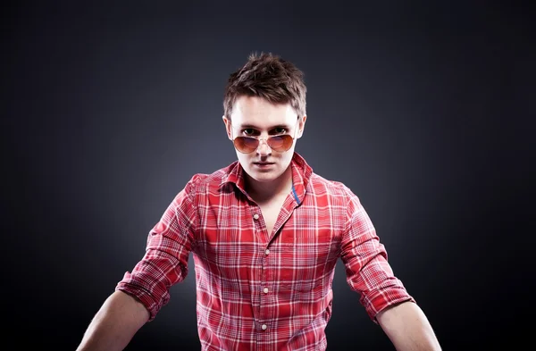 Handsome young man with sunglasses on dark background — Stock Photo, Image