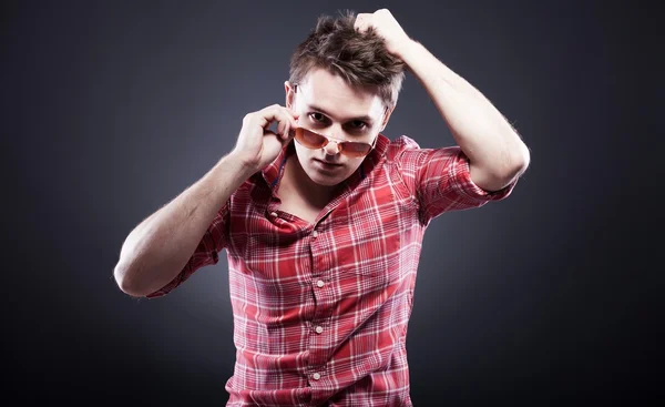 Handsome young man with sunglasses on dark background — Stock Photo, Image