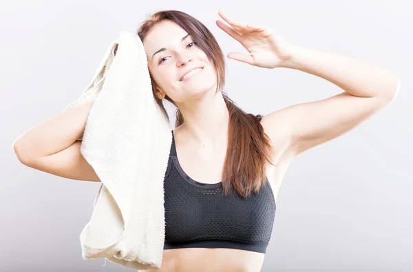 Souriant épuisé jeune femme après l'entraînement avec serviette — Photo