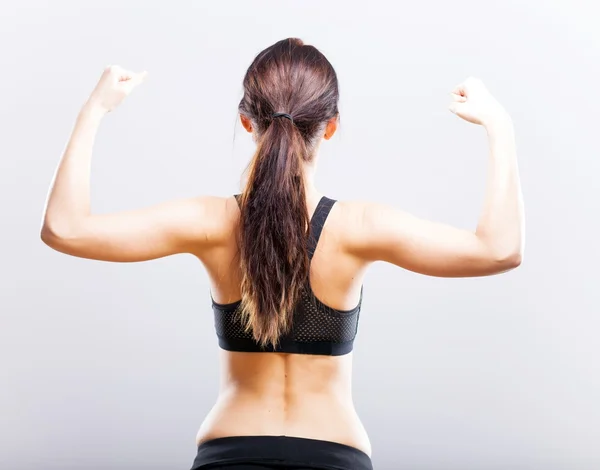 Fit mulher flexionando seu bíceps, visão traseira — Fotografia de Stock