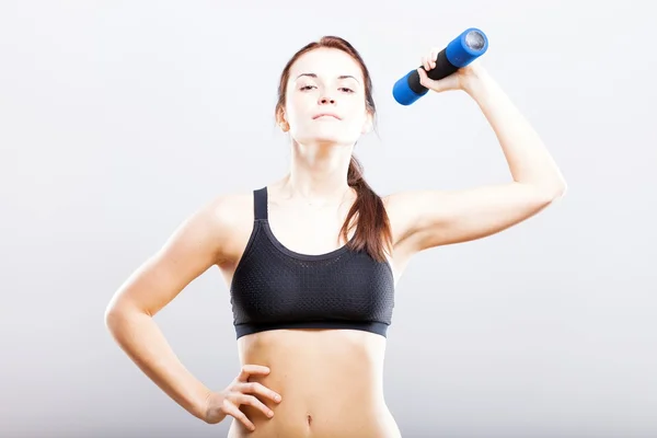 Jovem mulher em forma de sutiã esporte durante o exercício com halteres — Fotografia de Stock