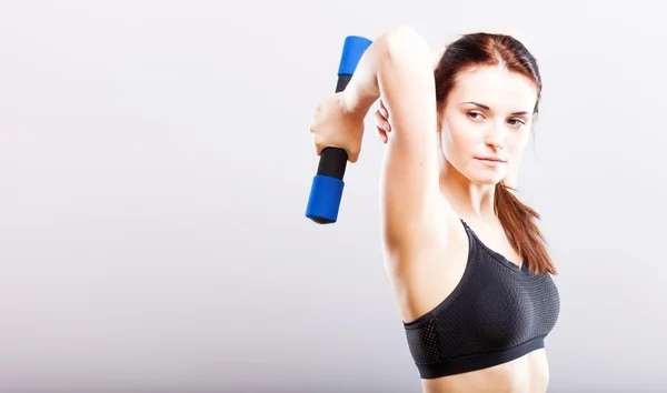 Jovem mulher em forma de sutiã esporte durante o exercício com halteres — Fotografia de Stock