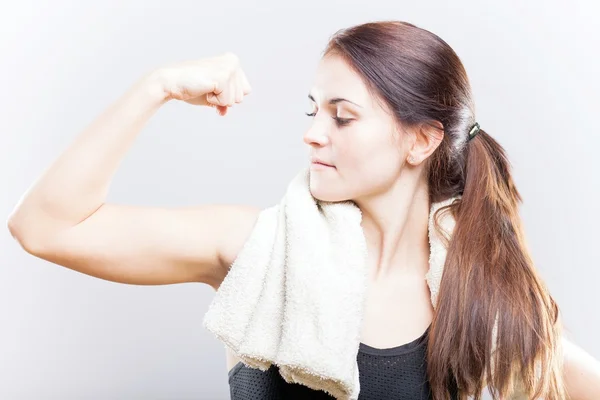 Ung vältränad kvinna tittar på hennes biceps efter träning — Stockfoto