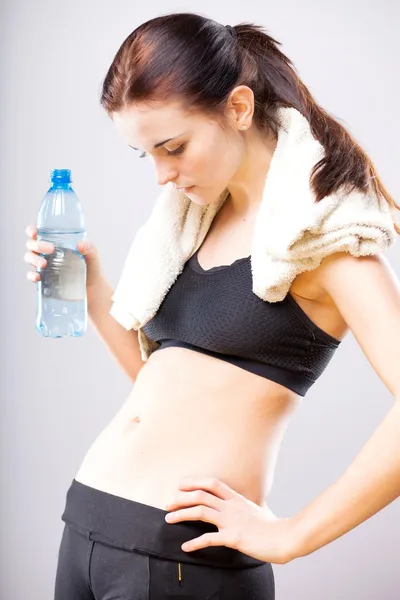 Woman looking at her flat stomach with water bottle — Stock Photo, Image