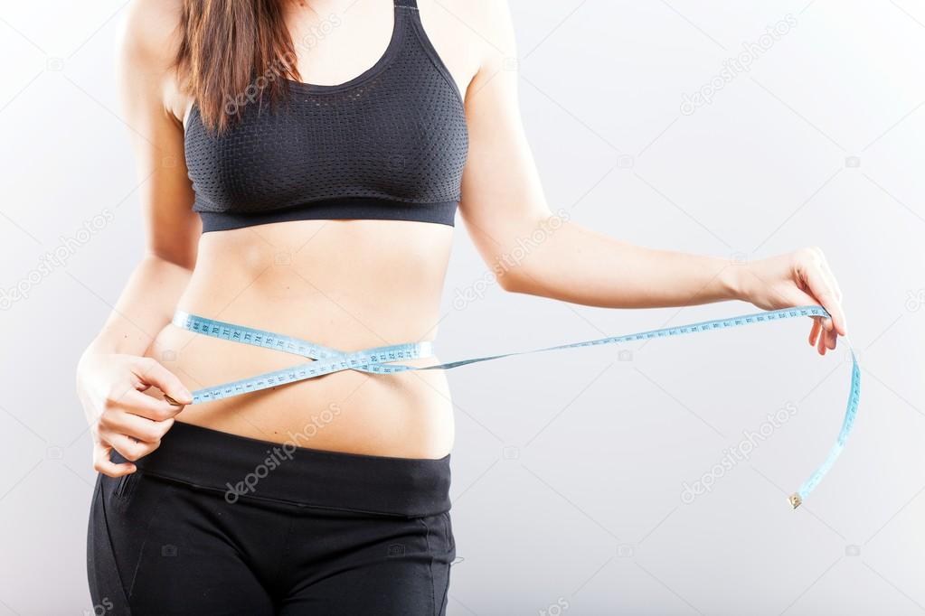 Fitness woman measuring her waistline