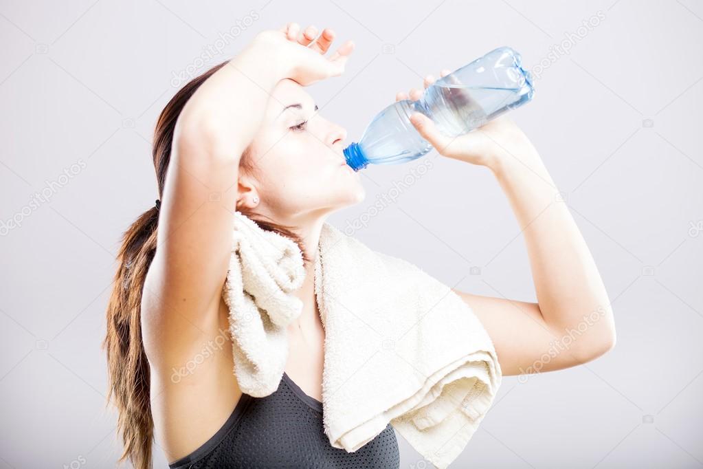 Attractive woman drinking water after exercise
