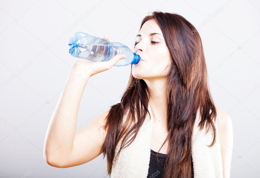 Young fit woman drinking water after fitness