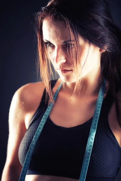 Tired fitness woman after exercise with measuring tape — Stock Photo, Image