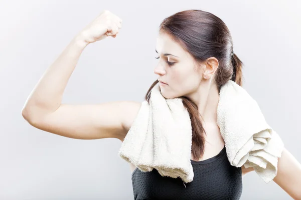 Sporty woman looking at her biceps after exercise — Stock Photo, Image