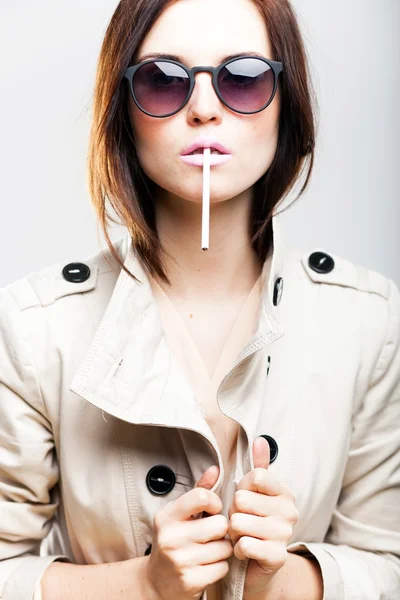 Fashionable woman in white coat with sunglasses and cigarette — Stock Photo, Image