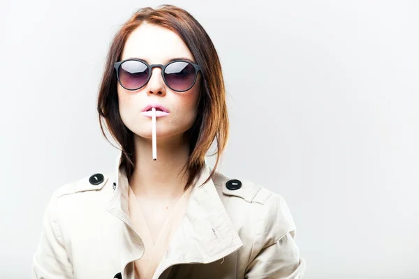 Fashionable woman in coat and sunglasses with cigarette — Stock Photo, Image