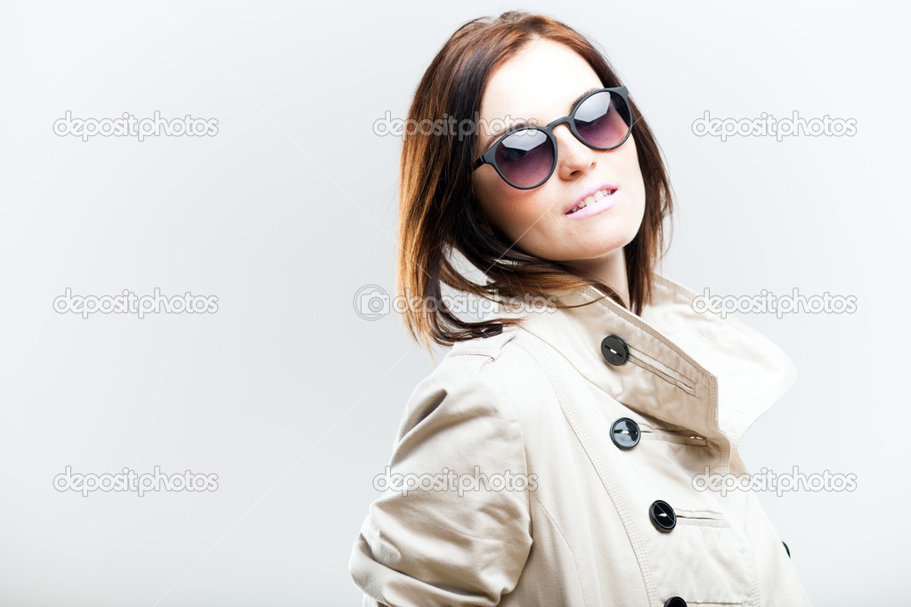 Smiling fashionable woman in coat with sunglasses