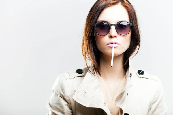 Fashionable woman in coat and sunglasses with cigarette — Stock Photo, Image