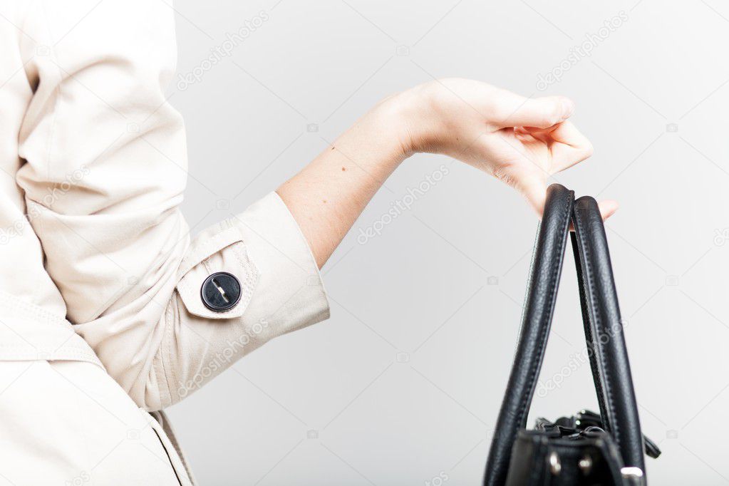 Elegant woman holding on finger black bag, back view