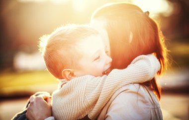 Mother hugging her child in the park clipart