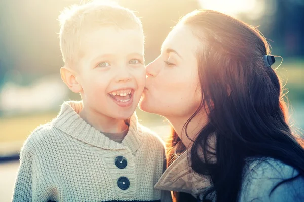 Mutter küsst ihr Kind beim Spaziergang — Stockfoto