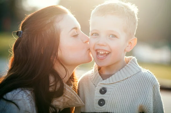 Junge Mutter küsst Kind im Freien — Stockfoto