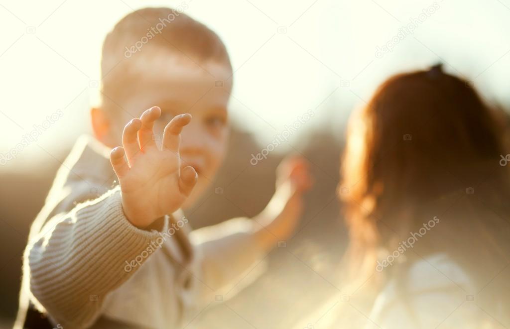 Child waving hand, boy with mother outdoor