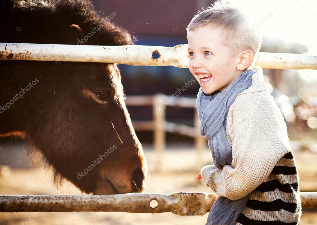 Smiling child with pony in mini zoo