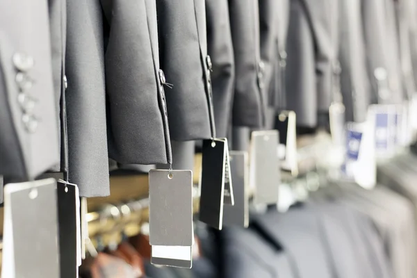 Fila di eleganti abiti giacca su appendini, negozio di abbigliamento — Foto Stock