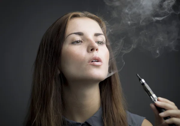 Elegante mujer fumando cigarrillo electrónico con humo —  Fotos de Stock