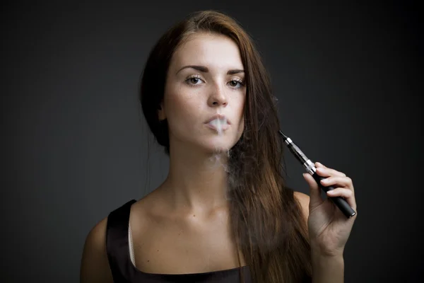 Elegante mujer fumando cigarrillo electrónico con humo — Foto de Stock