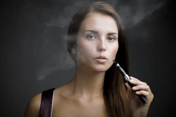 Elegante mujer fumando cigarrillo electrónico con humo — Foto de Stock