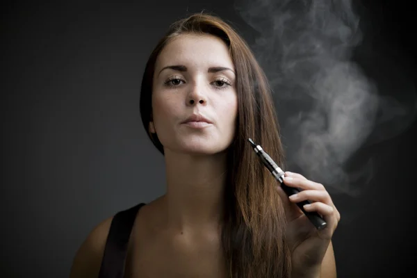 Elegante mujer fumando cigarrillo electrónico con humo — Foto de Stock