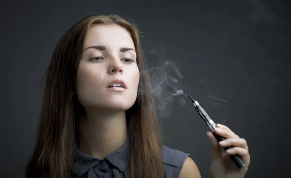 Элегантная женщина курит электронную сигарету с дымом — стоковое фото