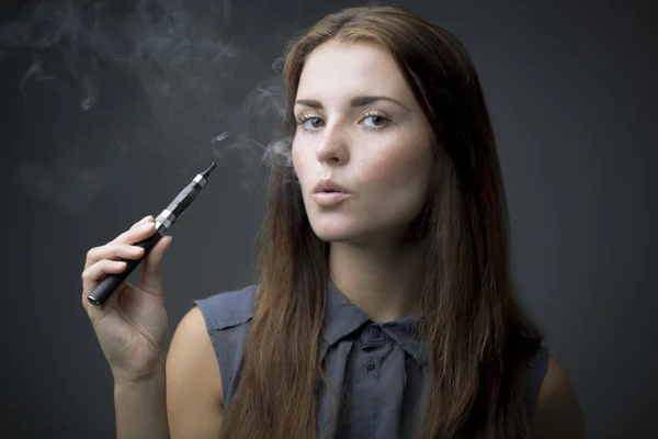 Elegante mujer fumando cigarrillo electrónico con humo —  Fotos de Stock