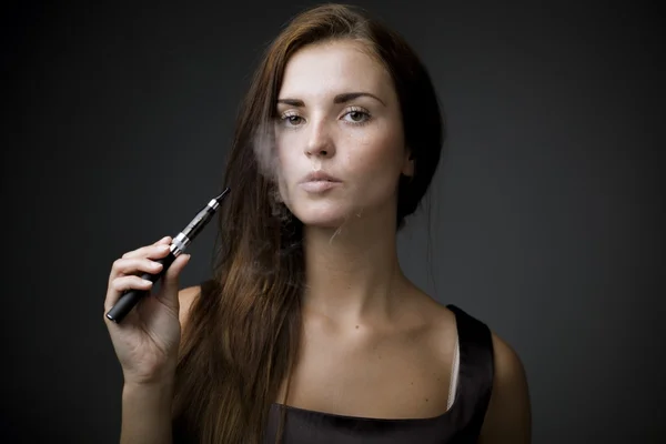 Elegante mujer fumando cigarrillo electrónico con humo — Foto de Stock