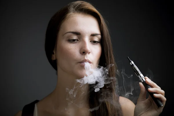 Elegante mujer fumando cigarrillo electrónico con humo — Foto de Stock