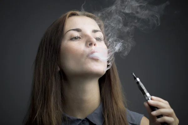 Elegante mujer fumando cigarrillo electrónico con humo — Foto de Stock