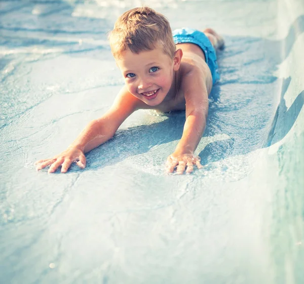 Niño en tobogán acuático en aquapark, vacaciones de verano — Foto de Stock