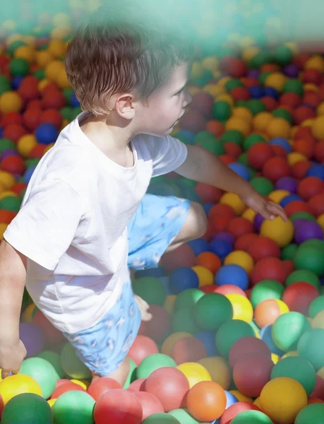 Malý chlapec hraje v barevné koule hřiště — Stock fotografie