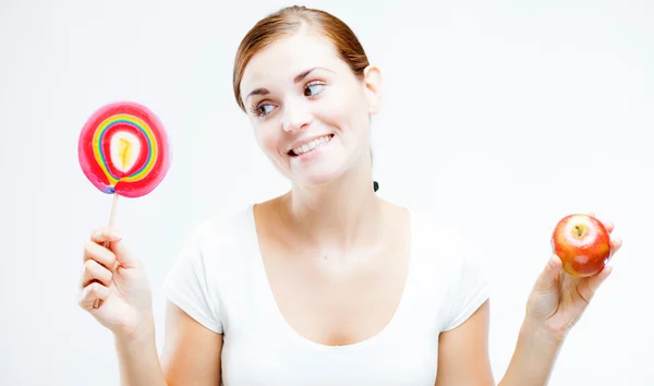 Woman choosing between sweets and fruits — Stock Photo, Image