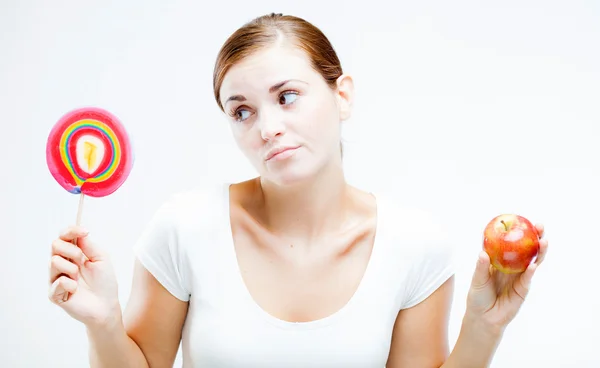 Mujer eligiendo entre dulces y frutas —  Fotos de Stock